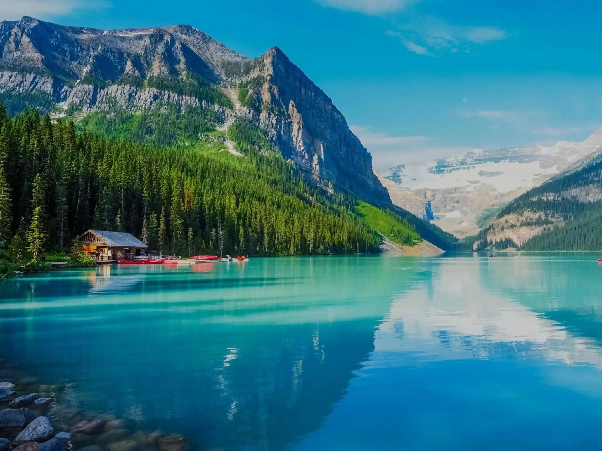Turquoise waters of Lake Louise surrounded by forested slopes and snow-capped mountains