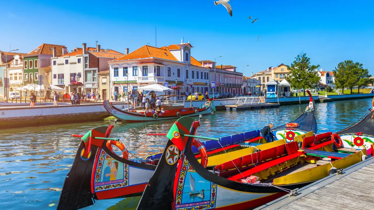 Brightly painted gondola-style boats moored along a canal lined with colourful buildings in Aveiro, Portugal