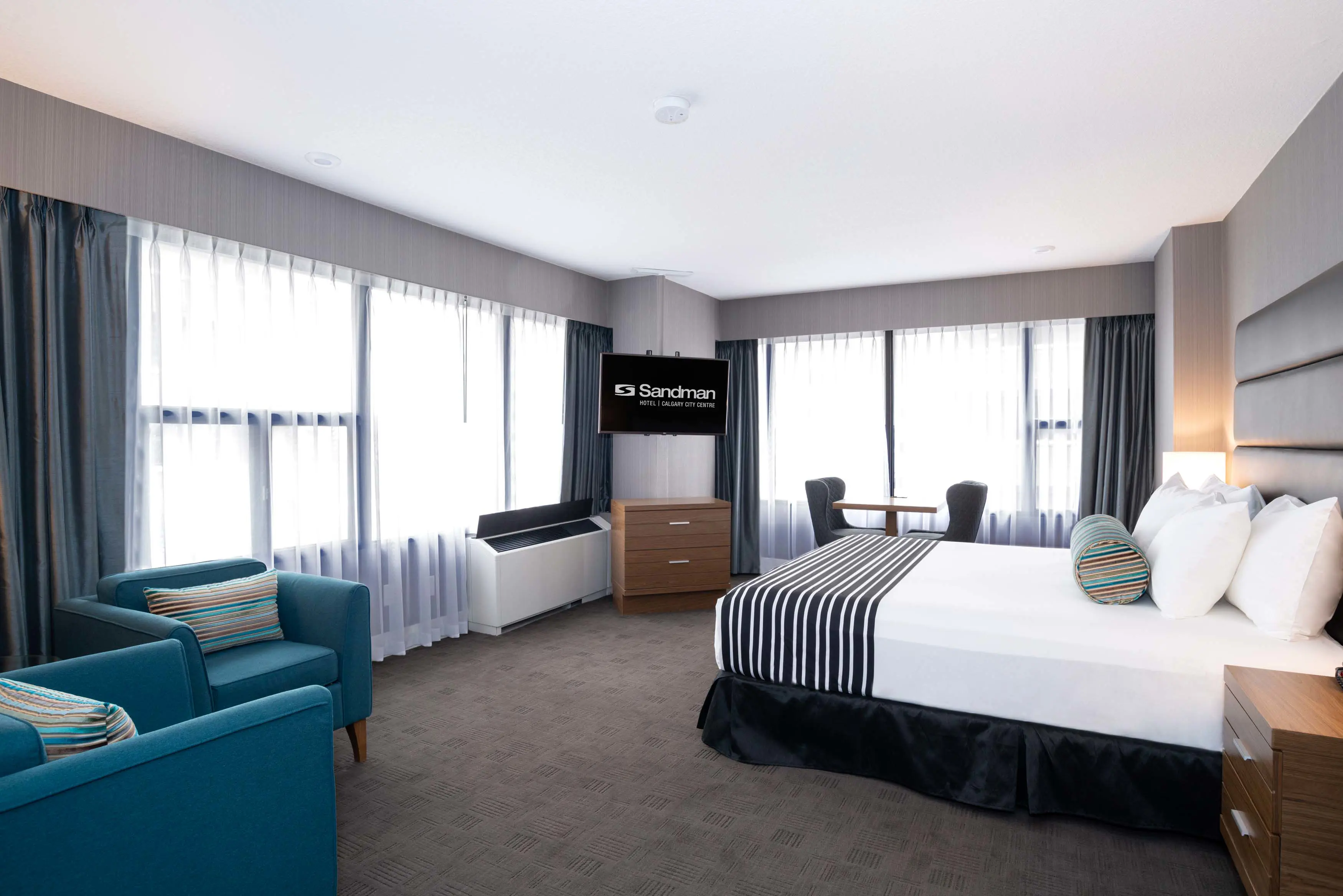 A king room at Sandman Signature Calgary Downtown, featuring a spacious layout and modern furnishings