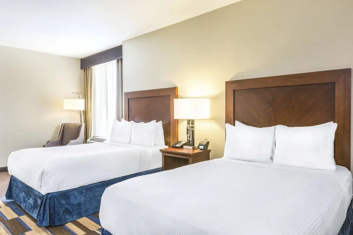 Spacious hotel room at Wyndham New Orleans French Quarter featuring two double beds with crisp white linens and large window