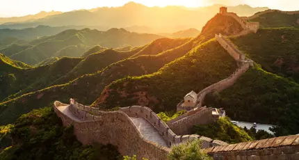 The Great Wall winding over green mountains at sunset, Beijing, China