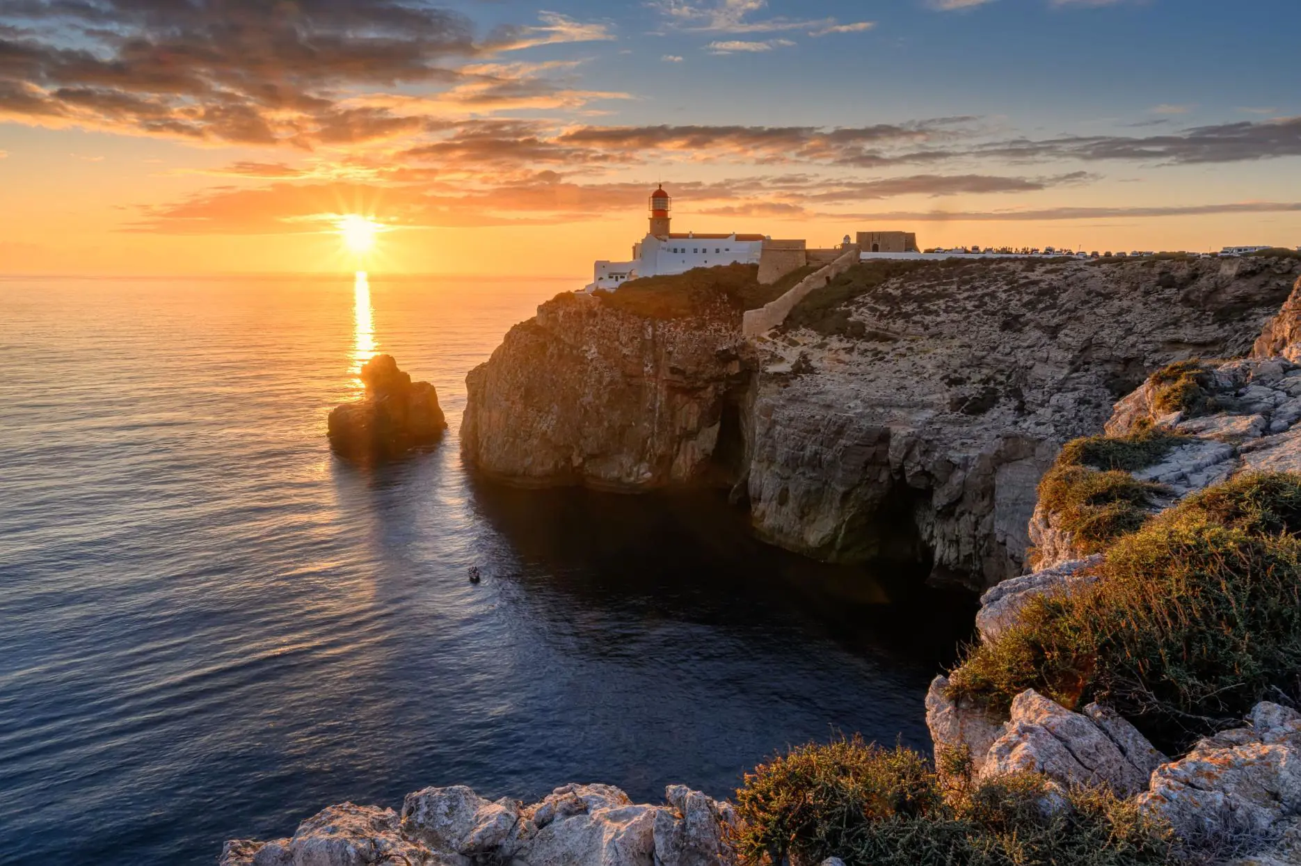 Lighthouse on the cliffs at Cape St. Vincent on the Algarve at sunset, with a colourful sky in the distance