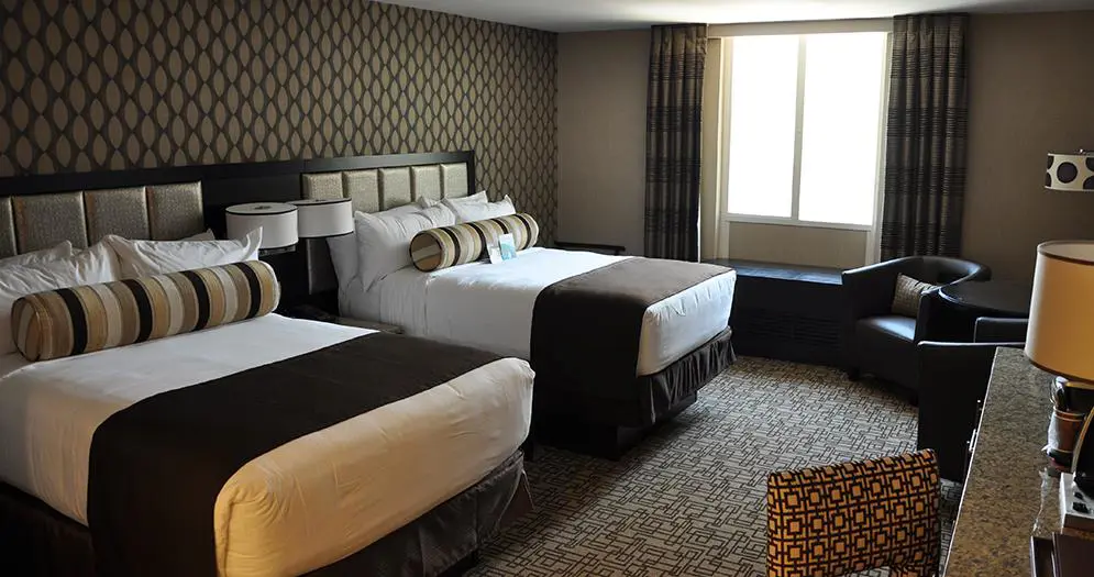 Comfortable twin double room at the Golden Nugget Hotel, Las Vegas, featuring two double beds with white linens, dark brown décor and patterned wallpaper