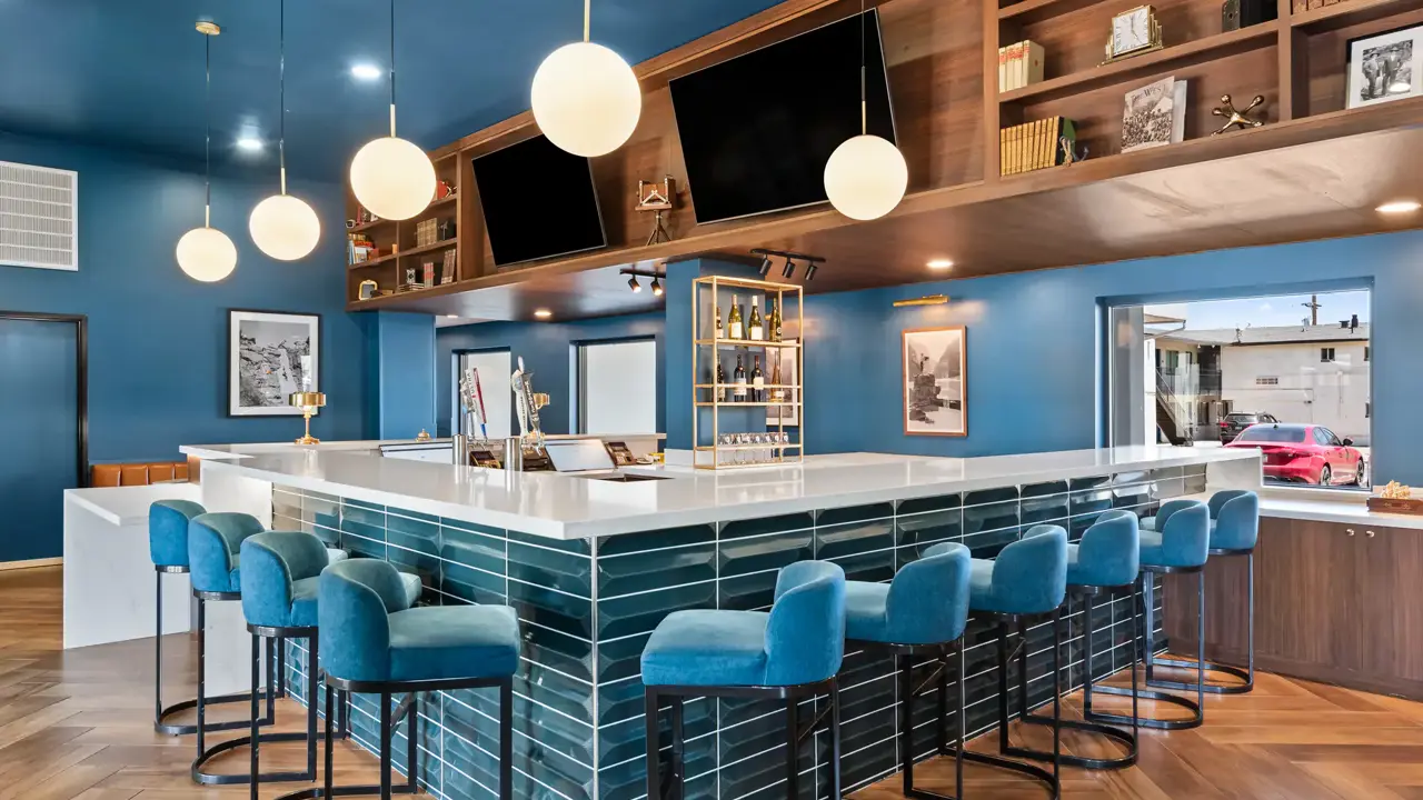 Cosy hotel bar at The Ellsworth Hotel, with dark wood and blue accents, featuring a polished bar counter, stools, and ambient lighting