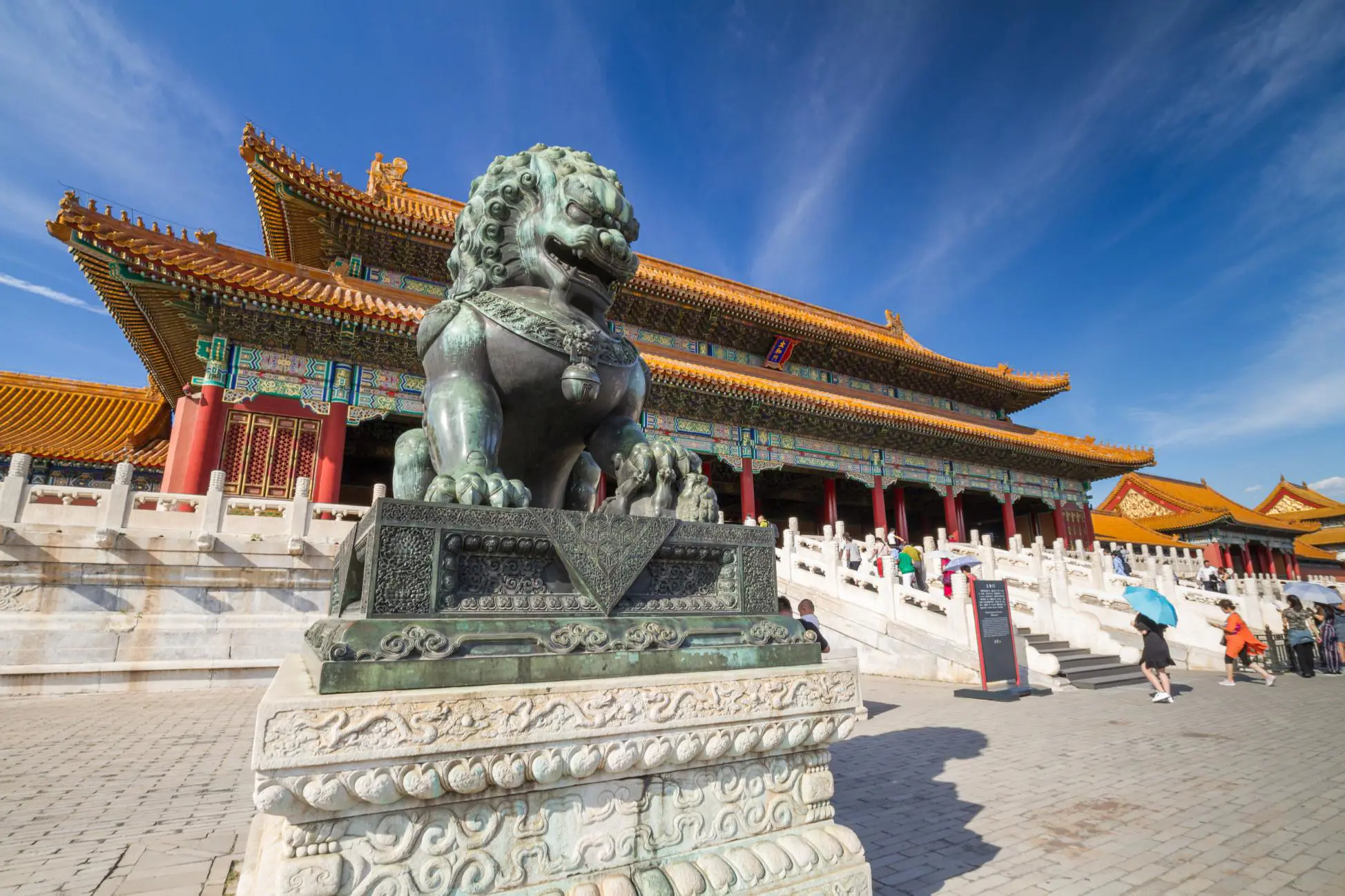 Bronze guardian lion outside ornate palace buildings in the Forbidden City, Beijing, China