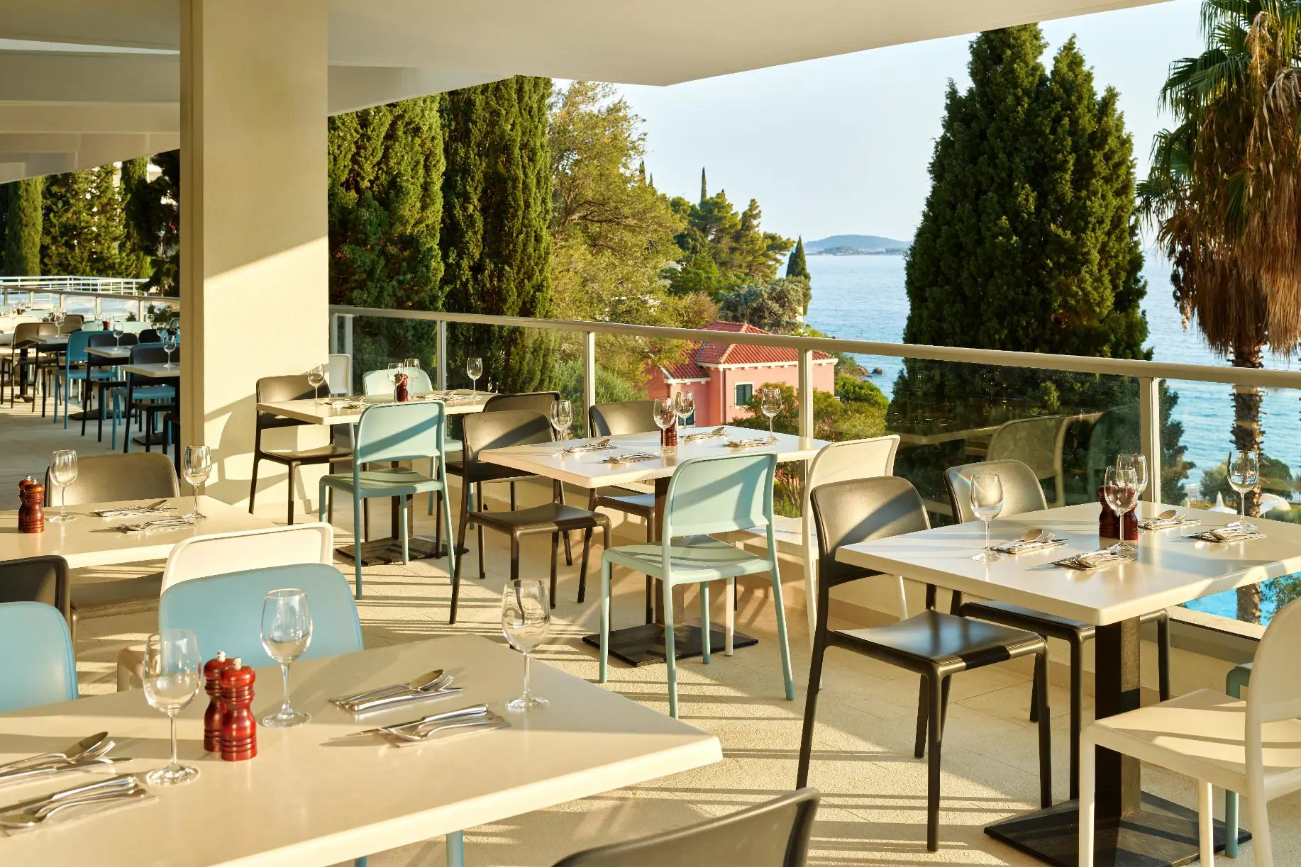 Veranda bar and restaurant with seating and tables at Hotel Horizont, Baška Voda. The veranda overlooks the sea and landscapes
