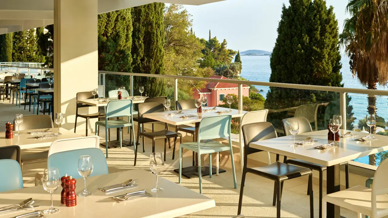 Veranda bar and restaurant with seating and tables at Hotel Horizont, Baška Voda. The veranda overlooks the sea and landscapes
