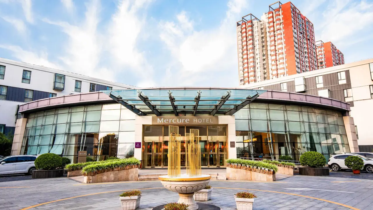 Exterior view of the Mercure Beijing Downtown hotel with a small fountain and potted plants in front of the modern glass entrance in Beijing, China