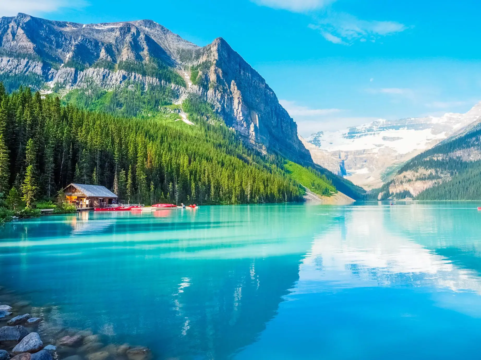 Turquoise waters of Lake Louise surrounded by forested slopes and snow-capped mountains