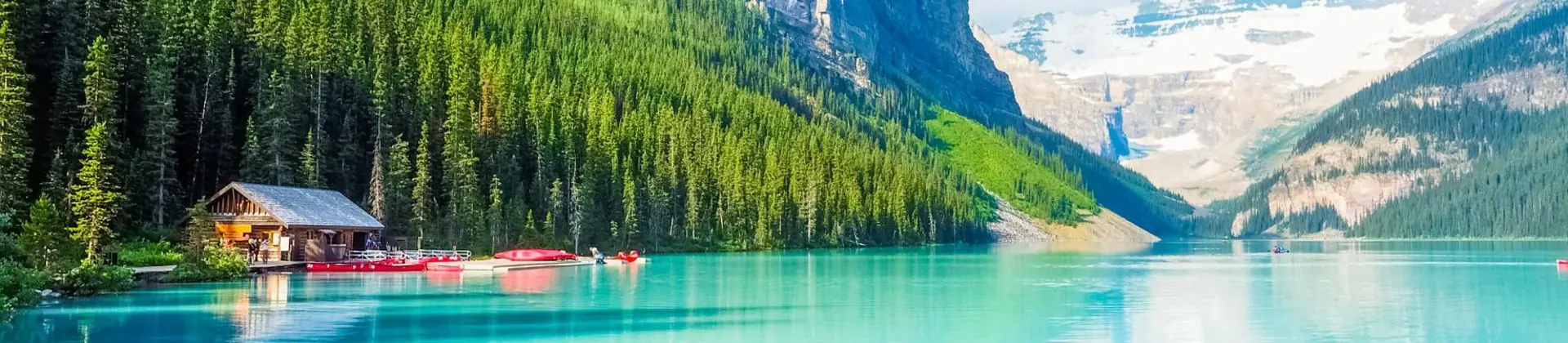 Turquoise waters of Lake Louise surrounded by forested slopes and snow-capped mountains