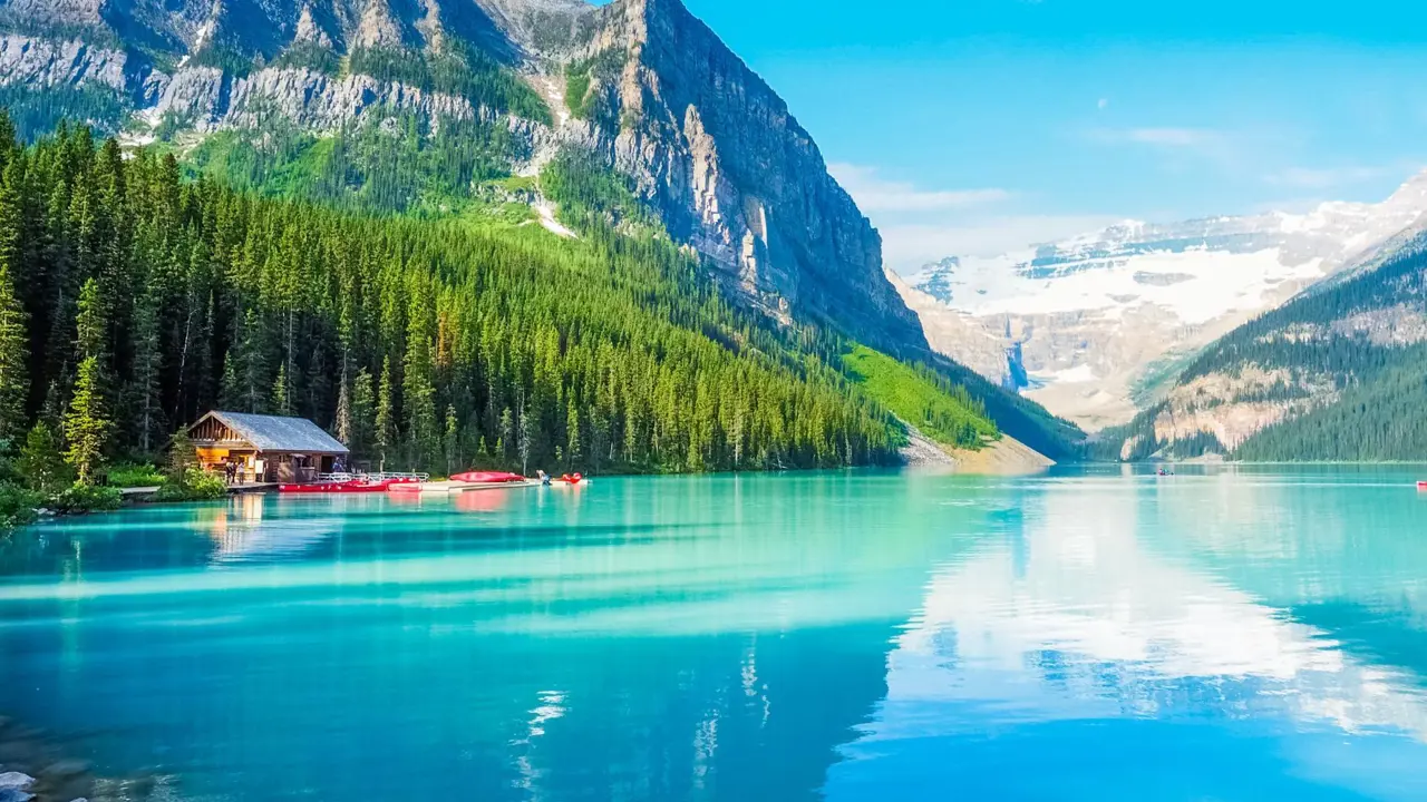 Turquoise waters of Lake Louise surrounded by forested slopes and snow-capped mountains