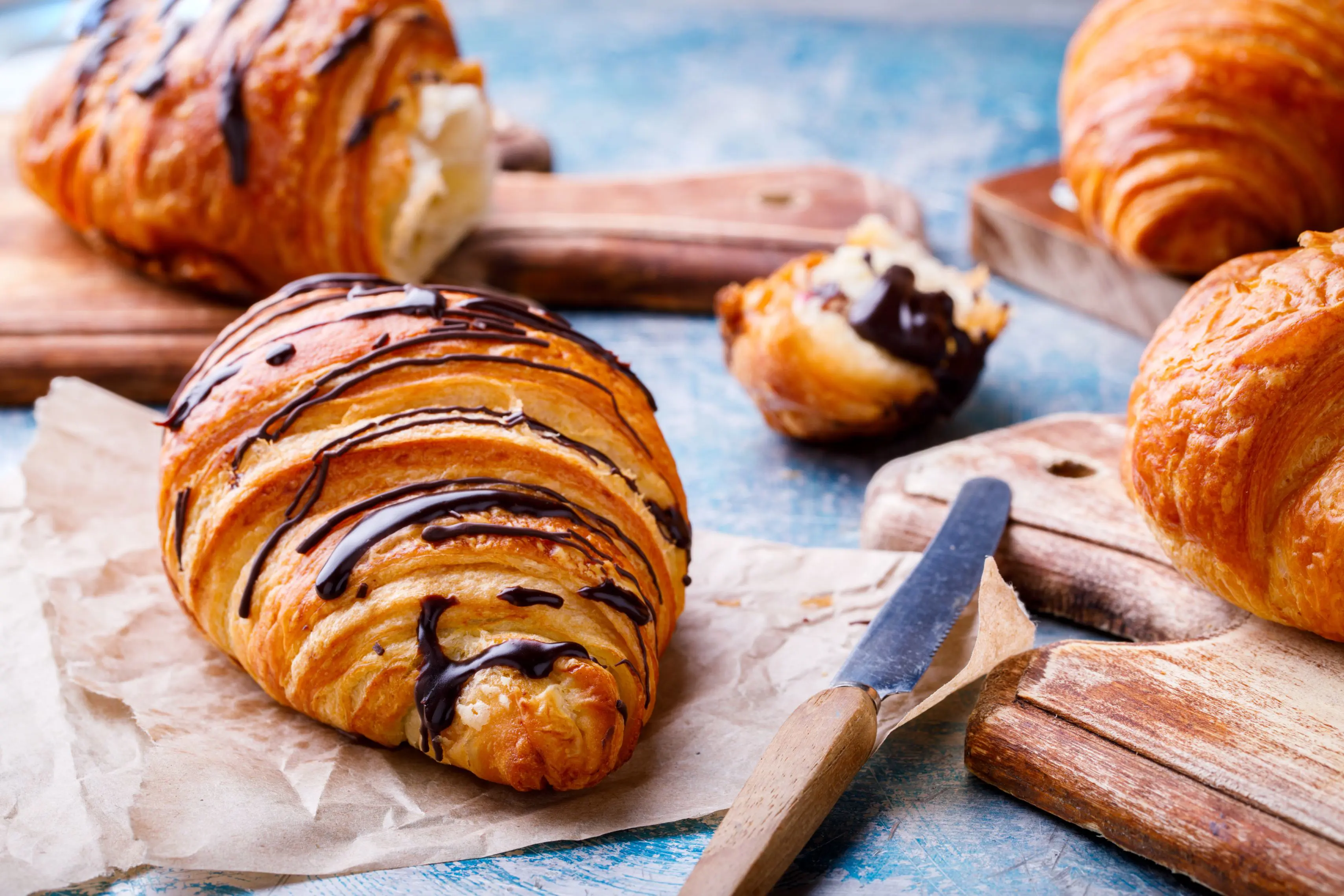 Chocolate croissants, one in the background which has been broken apart.