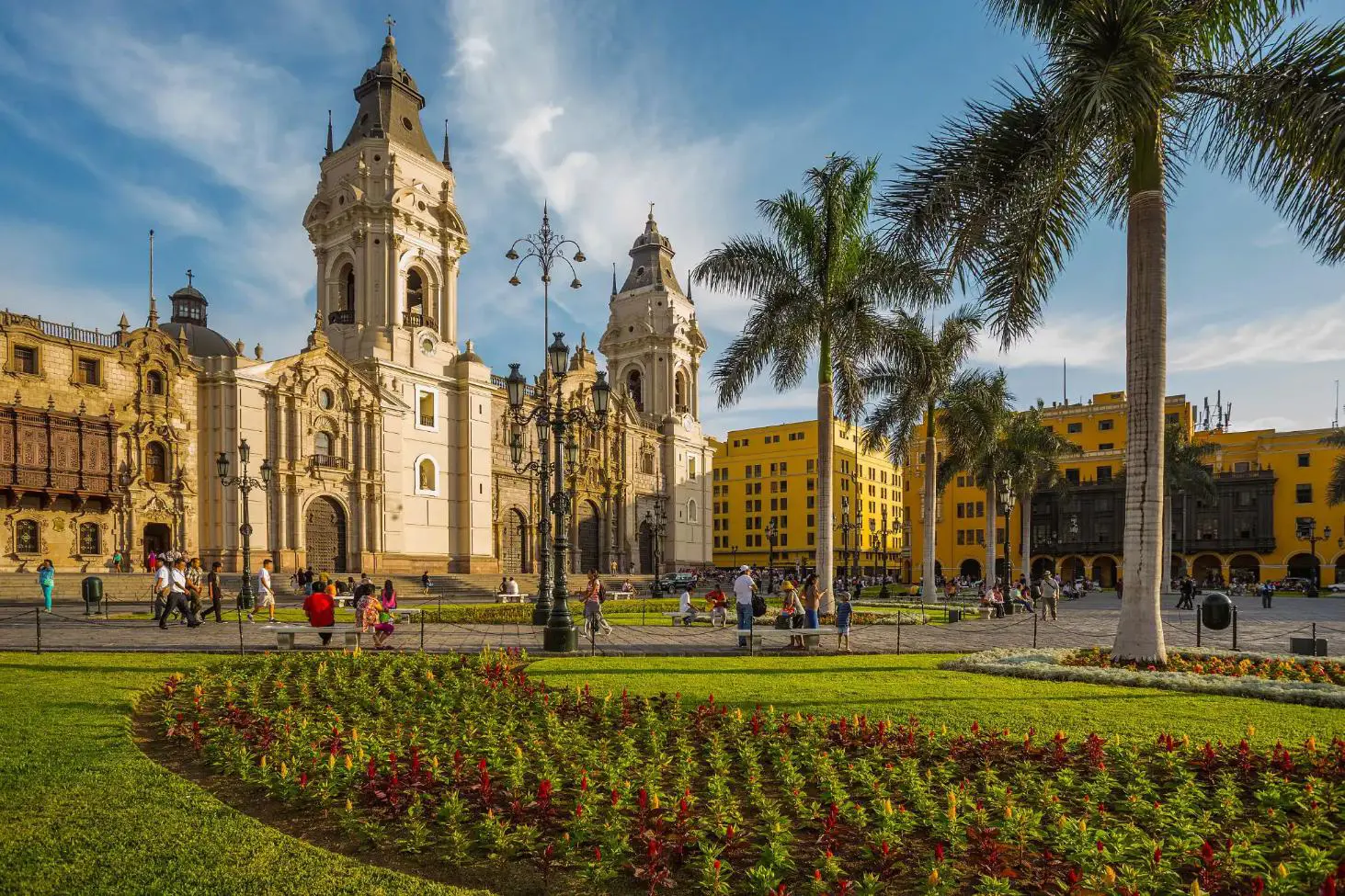A view of the Cathedral of Lima in the Main Square of Lima, Peru, featuring colonial architecture, palm trees, and a sunny sky in the background