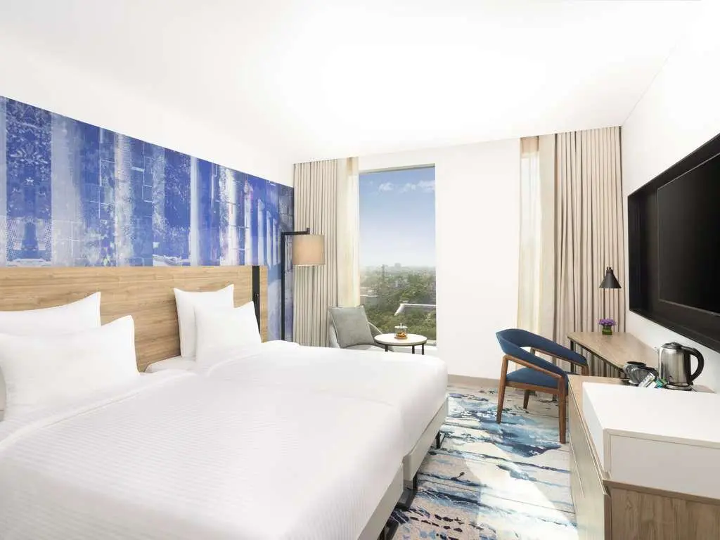 A bright twin guest room at Novotel New Delhi City Centre with two beds and a city view