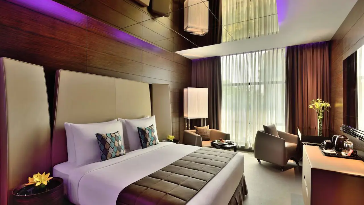 Smart deluxe room at Radisson Blu Atria in Bengaluru, featuring warm wooden décor and furnishings, with a large window fitted with blinds