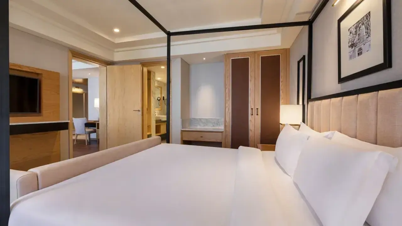 Double guest room at The Residency Towers hotel in Pondicherry, warmly lit and styled with clean white linens and light wooden furnishings