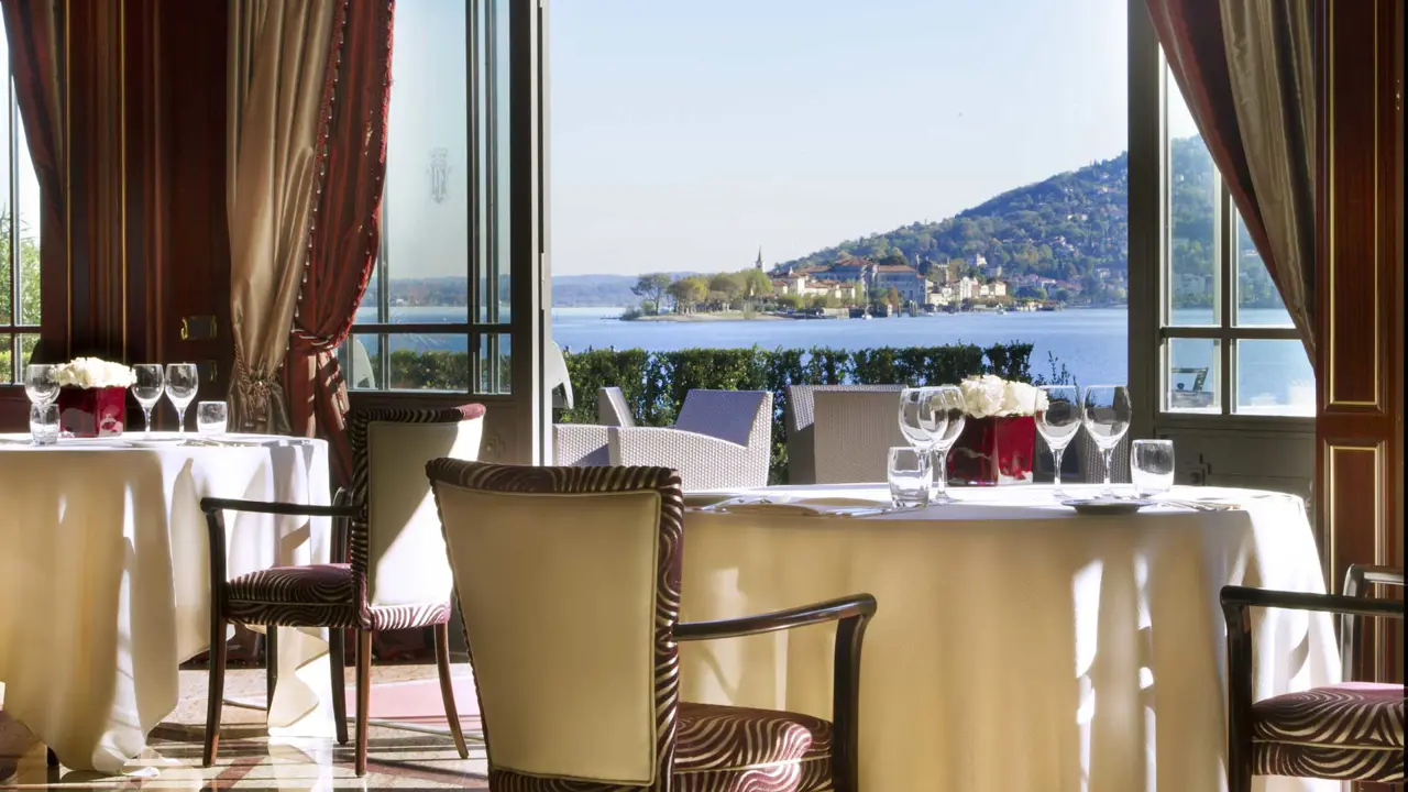 Bright dining area at Grand Hotel Dino in Baveno, with laid tables and large open glass doors offering a view of the lake