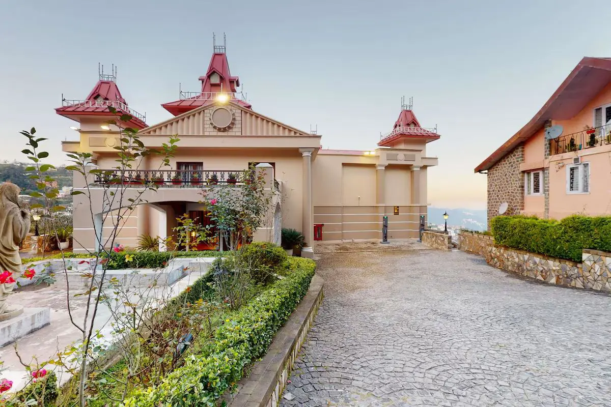 The hilltop exterior of Radisson Hotel Jass in Shimla with red-roofed towers and landscaped gardens