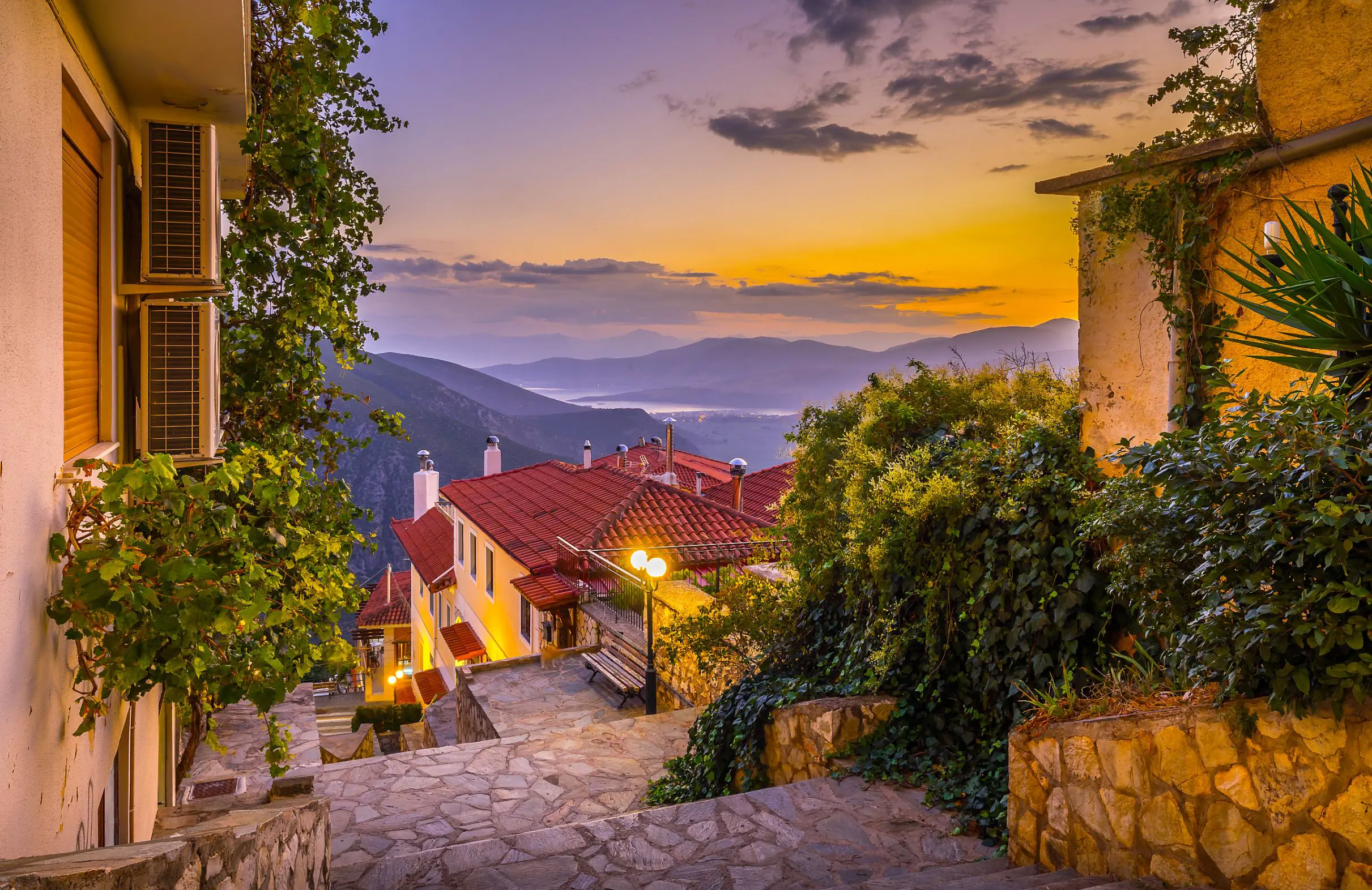 View from a village in the mountains, looking out on the landscape with sunset and silhouette of mountains. Steps and buildings in the forefront