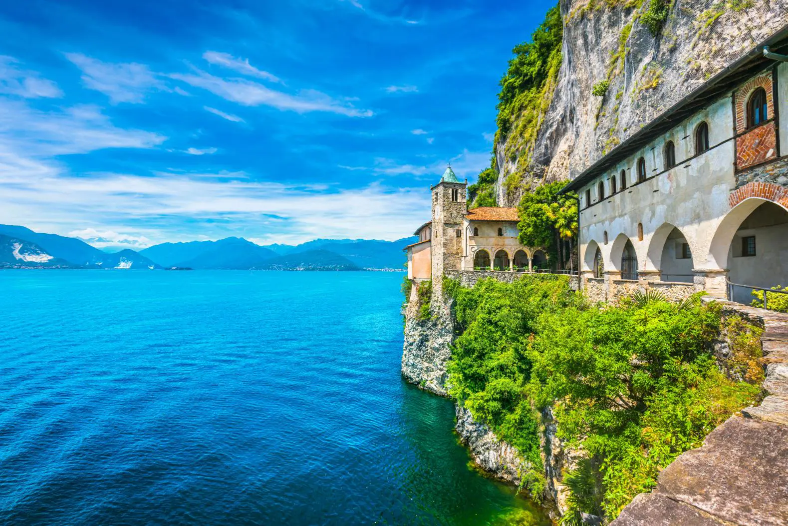 A scenic view of Lake Maggiore in Italy, with charming buildings along the water’s edge and mountains rising in the distance