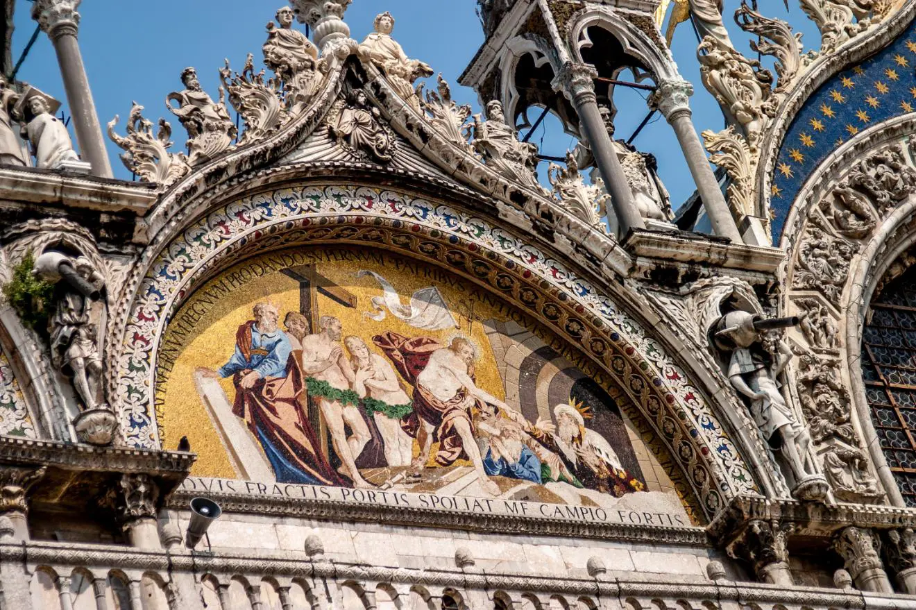 Intricate mosaics with vibrant gold backgrounds and detailed figures above the entrance of Saint Mark's Basilica in Venice, Italy