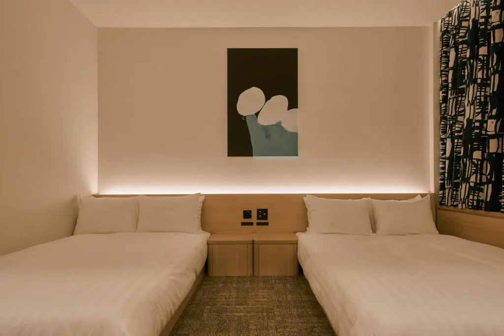 Minimalist double room at FAV LUX Nagasaki with two double beds, warm ambient lighting, and modern abstract artwork