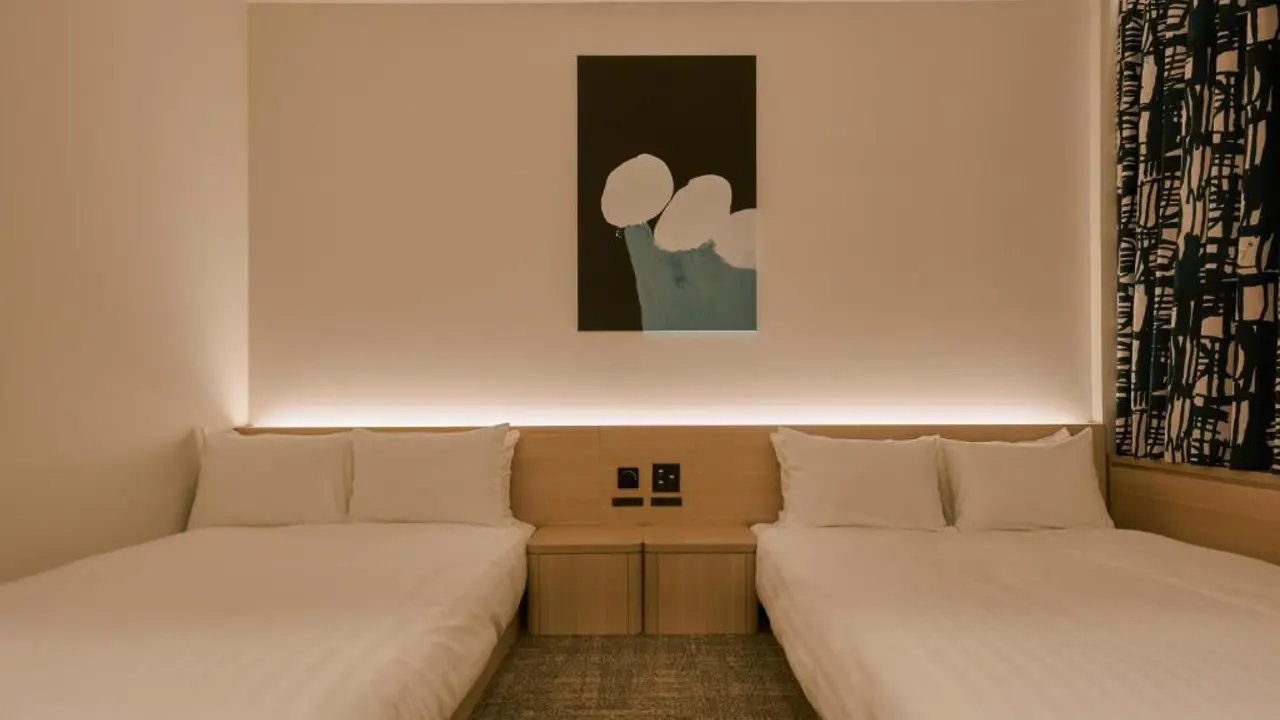 Minimalist double room at FAV LUX Nagasaki with two double beds, warm ambient lighting, and modern abstract artwork