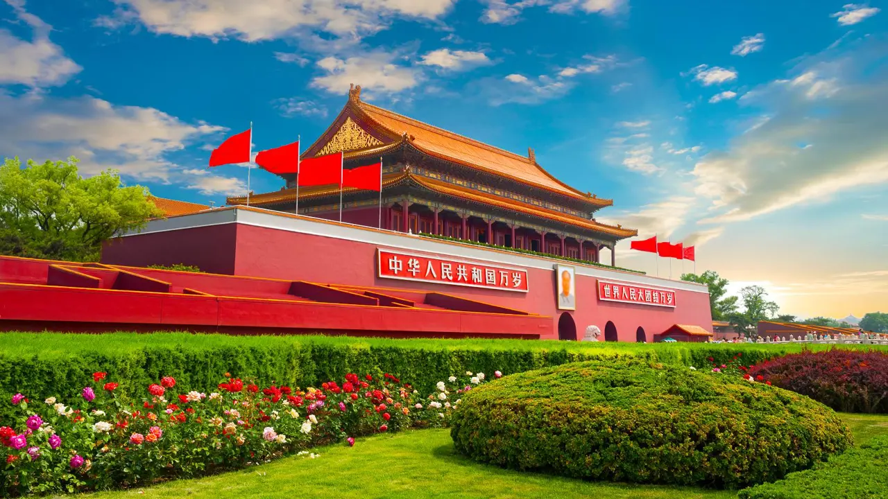 Tiananmen Gate with red flags and colourful gardens under a bright blue sky, Beijing, China