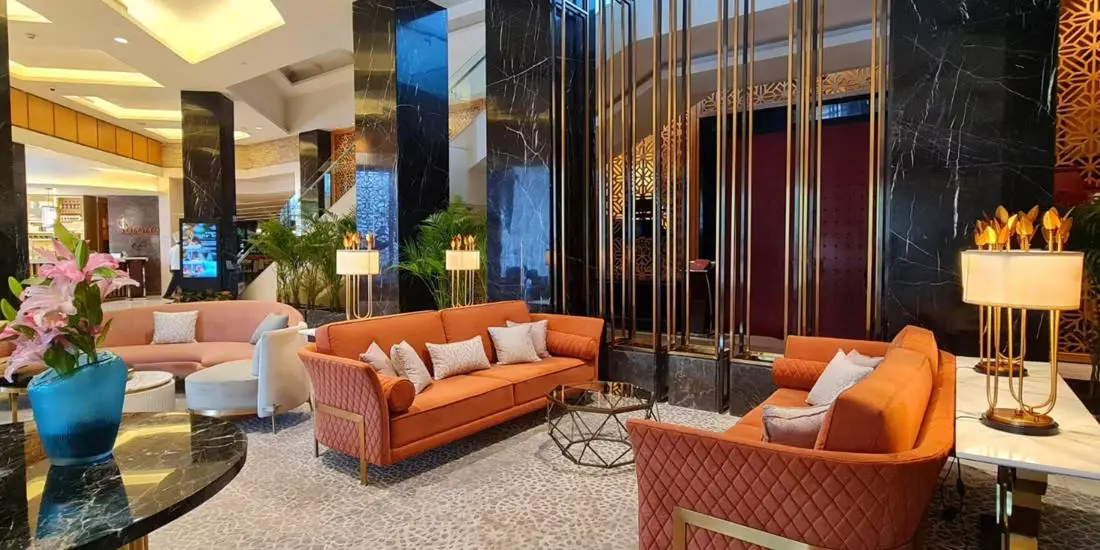 The elegant lobby of the InterContinental Jaipur featuring orange sofas, marble columns and gold accents