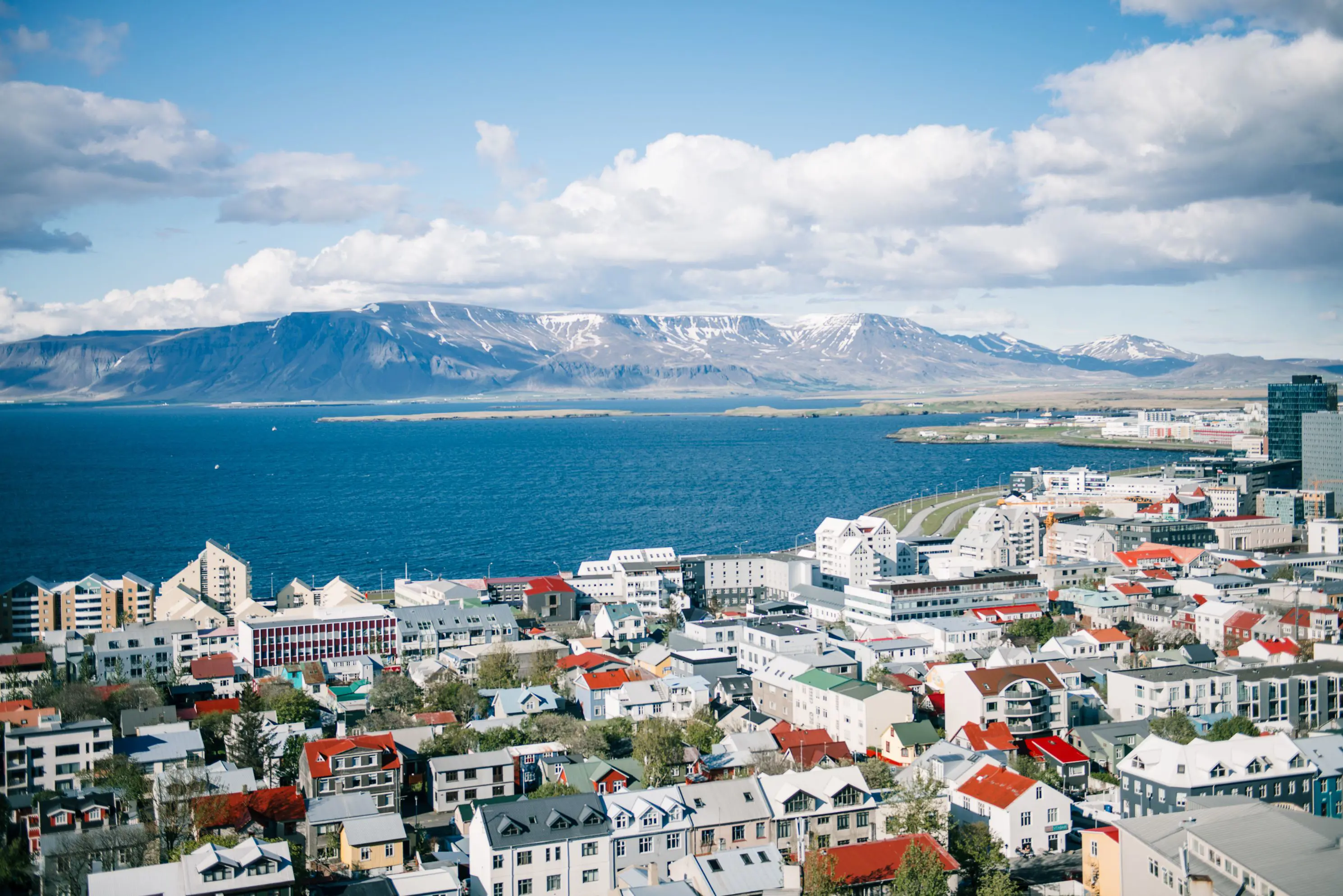 Predominately white houses and buildings of Reykjavik on the waterfront. View of mountains in the distance