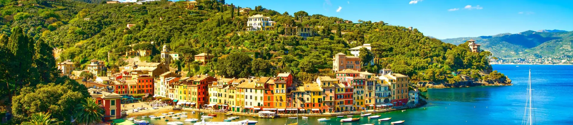 View of a small beach in Portofino, showing boats on the water and buildings on the waterfront