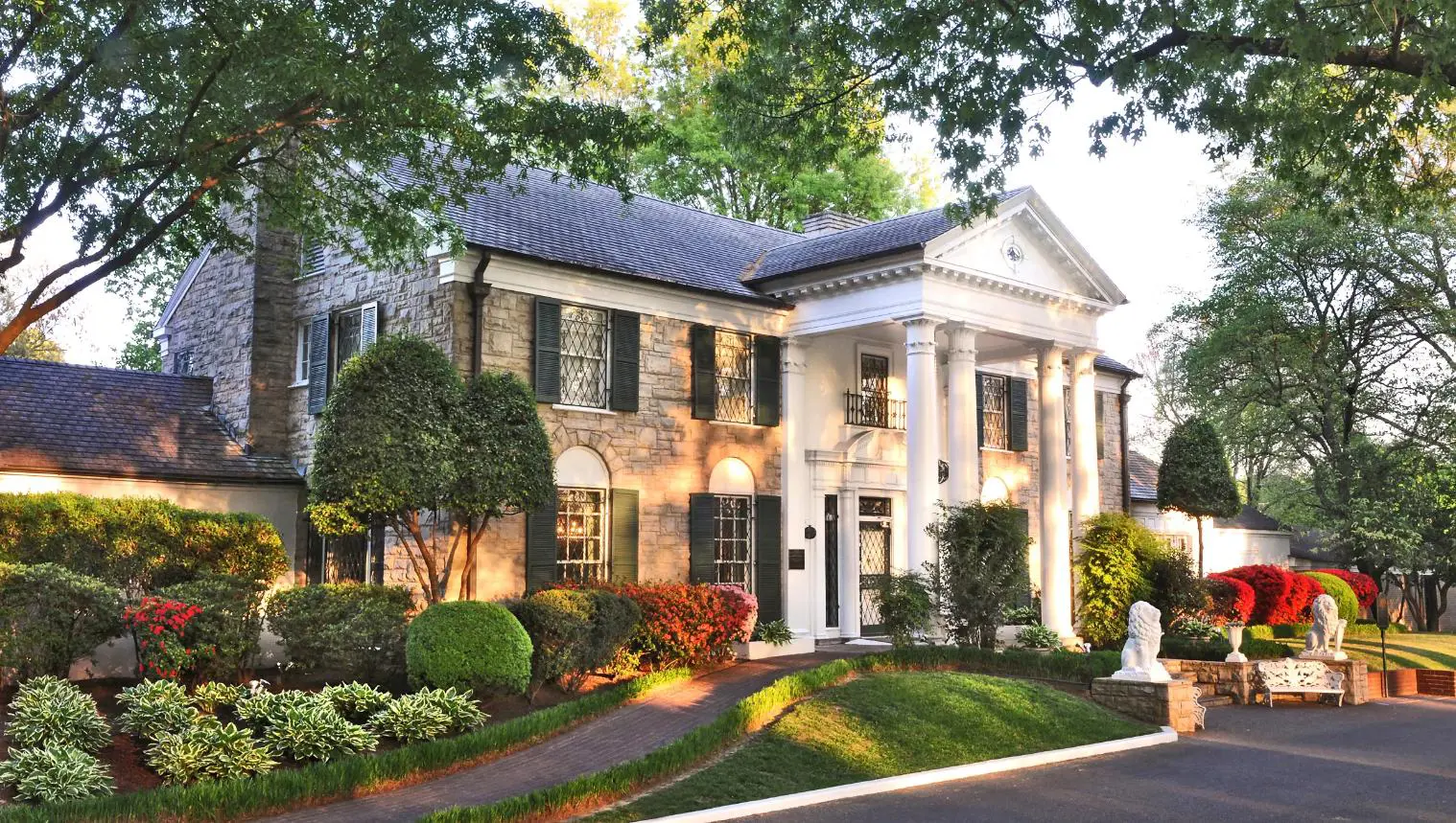 Graceland mansion in Memphis, Tennessee, the former home of Elvis Presley, featuring a grand white-columned façade surrounded by well-kept lawns and tall trees