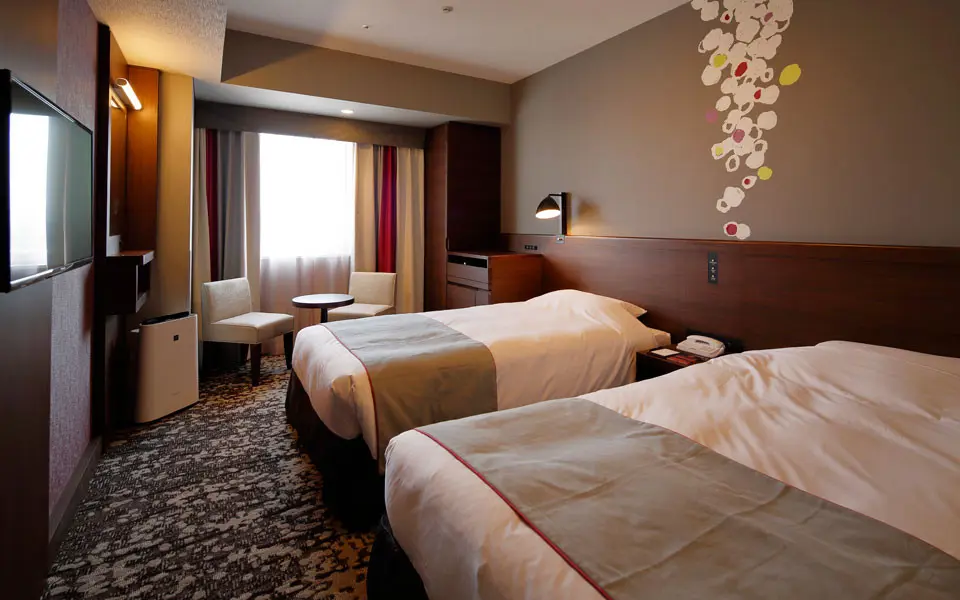 Comfortable standard twin room at Hotel Monte Hermana with two single beds, rich wood accents, patterned carpet, and seating by the window