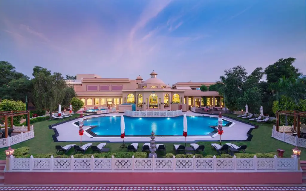 Outdoor pool at Heritage Village Resort and Spa, Gurugram, surrounded by sun loungers and landscaped gardens