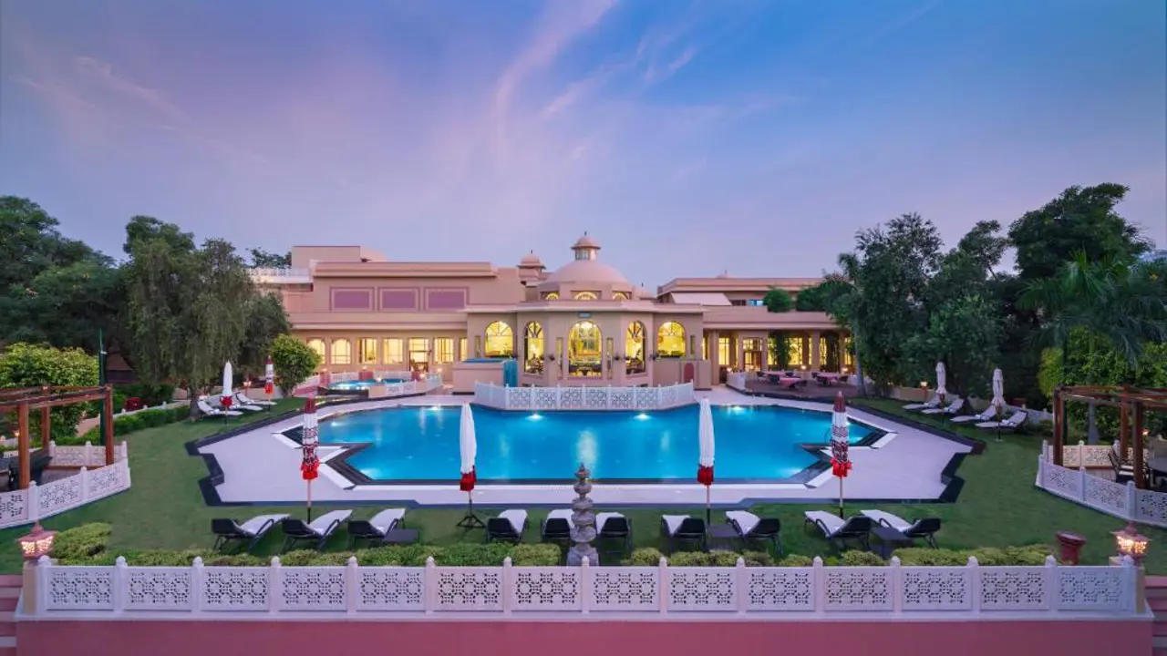 Outdoor pool at Heritage Village Resort and Spa, Gurugram, surrounded by sun loungers and landscaped gardens