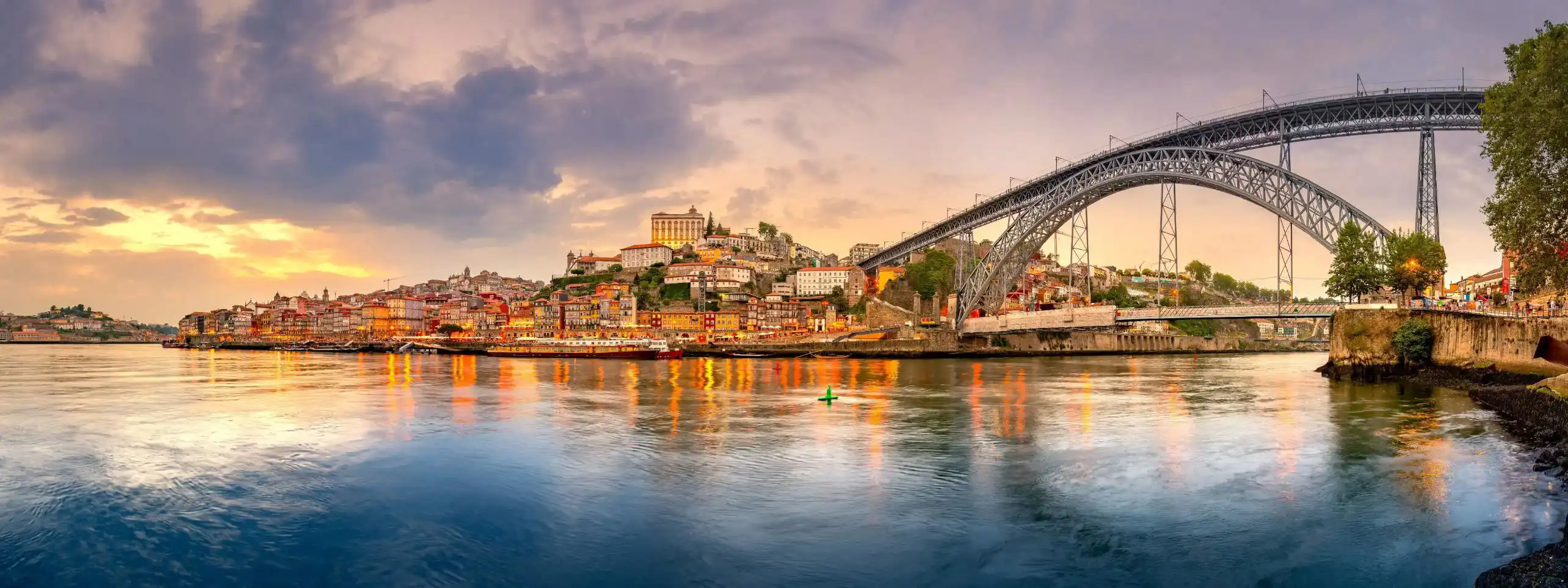 Picturesque view of Porto, Portugal, showing the Dom Luís I Bridge crossing the Douro River, with historic, colourful buildings along the riverbanks