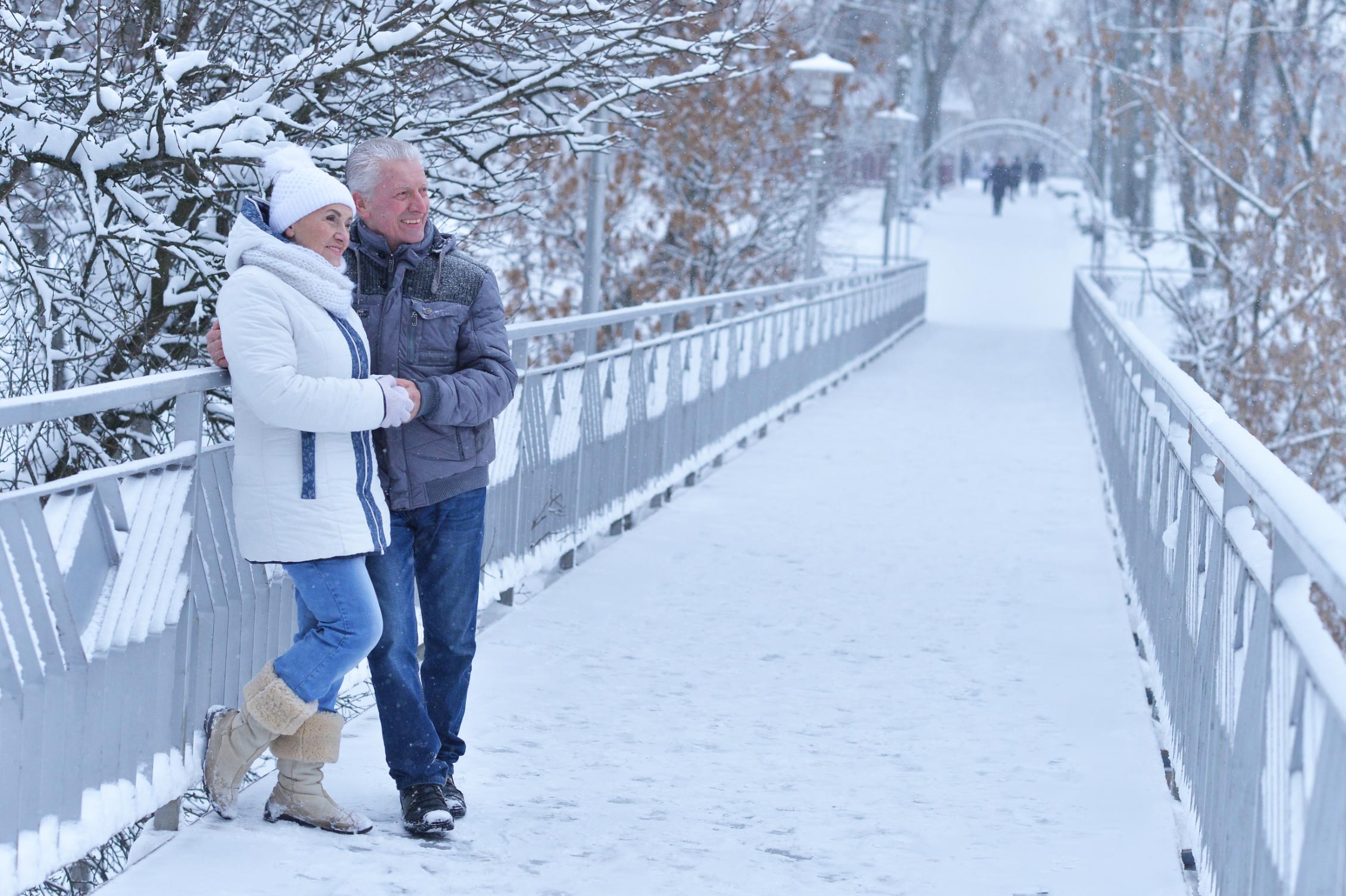 Sh_773598061 Senior mature couple in winter snow on a bridge