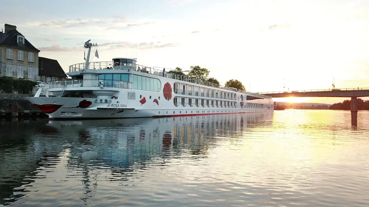 A-ROSA VIVA cruise ship on a calm city river at sunset, with a bridge in the background