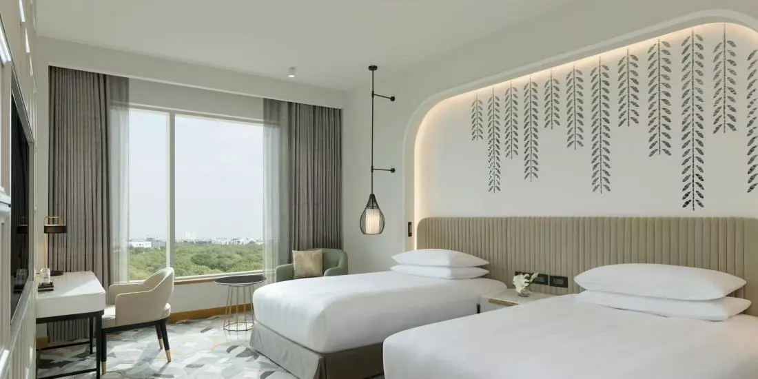 A modern hotel room with two single beds, soft lighting and a large window at the InterContinental in Jaipur