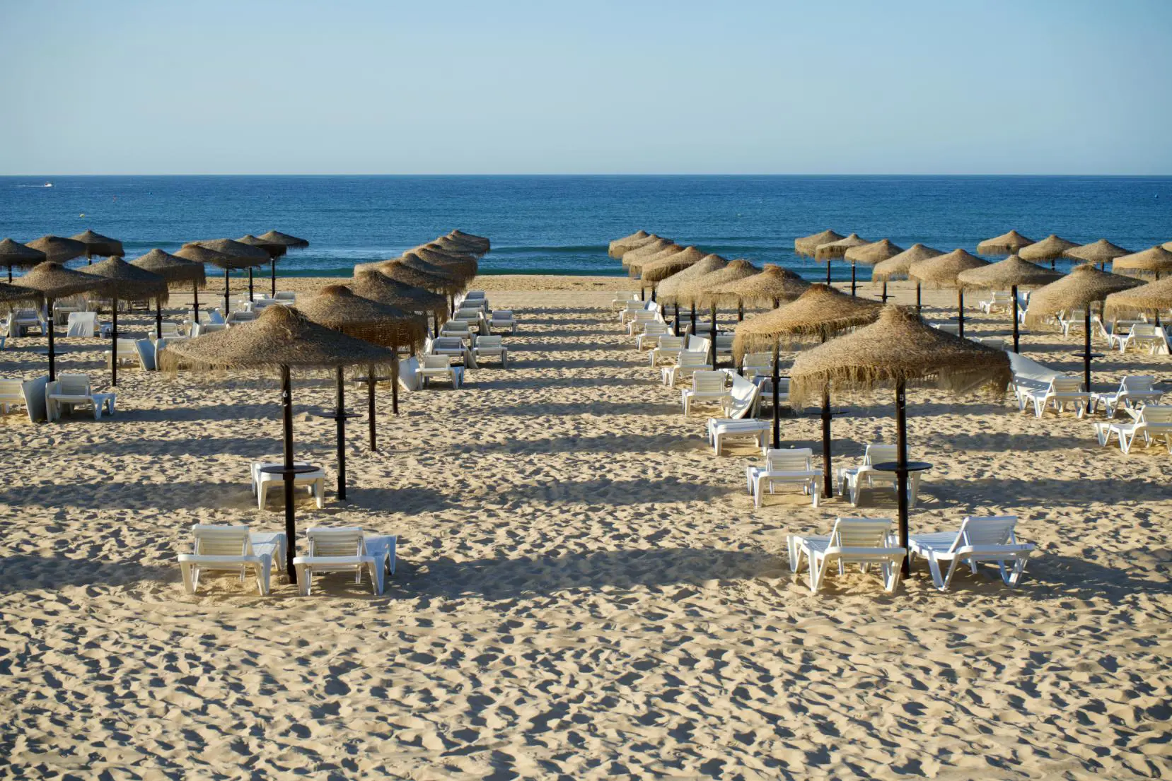 Beach at Praia de Monte Gordo on the Algarve with sunbeds and parasols on the sand, and the sea visible in the distance