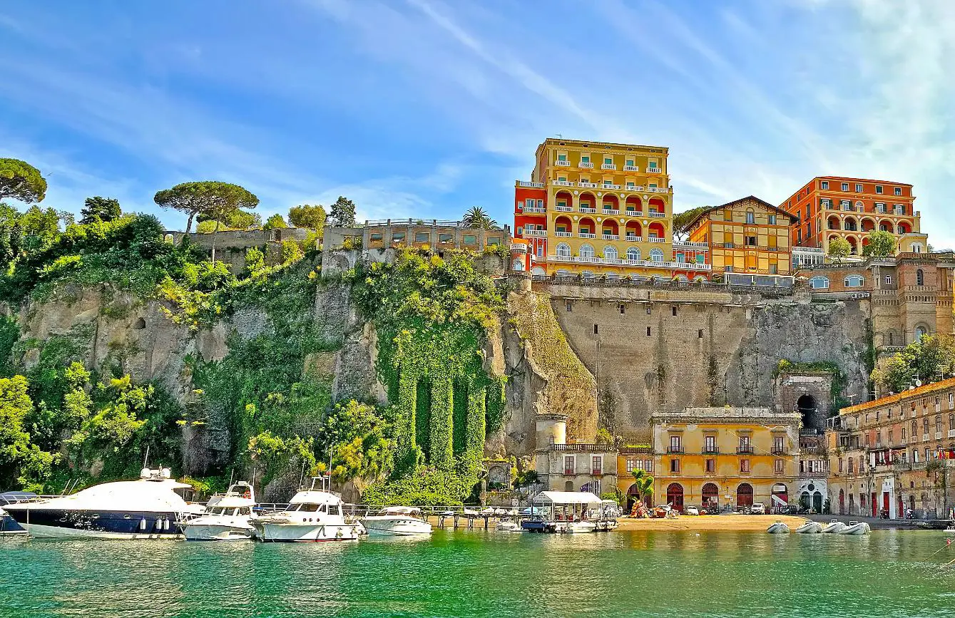 View of Sorrento from the water, with boats in the forefront and hotels and restaurants on the cliff top