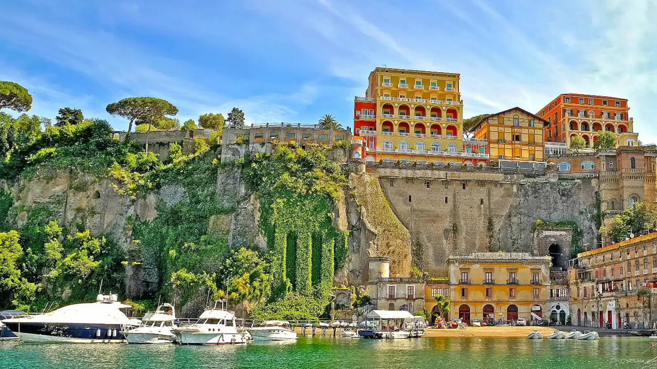 View of Sorrento from the water, with boats in the forefront and hotels and restaurants on the cliff top