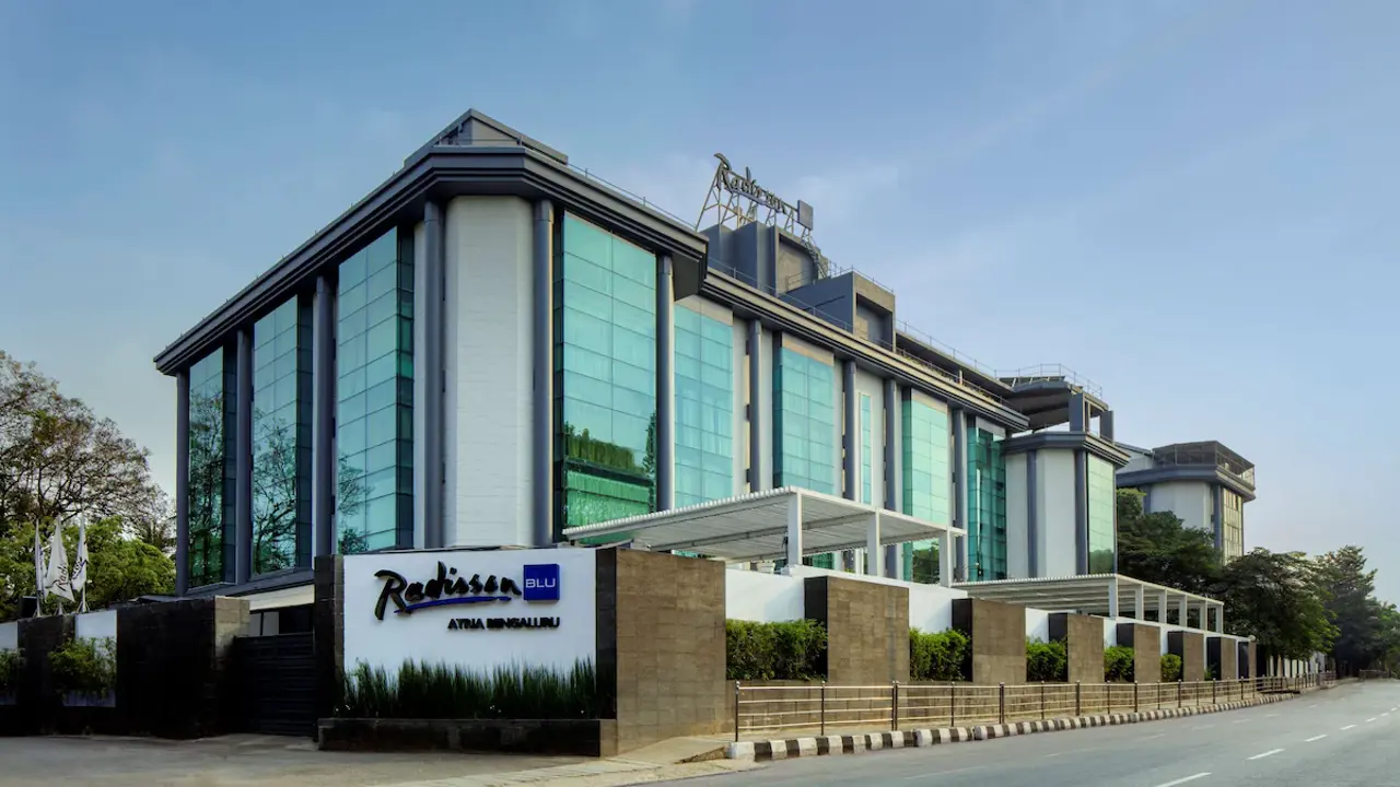 Exterior view of the Radisson Blu Atria hotel in Bengaluru, showcasing a contemporary design with tall glass façades and a stylish entrance