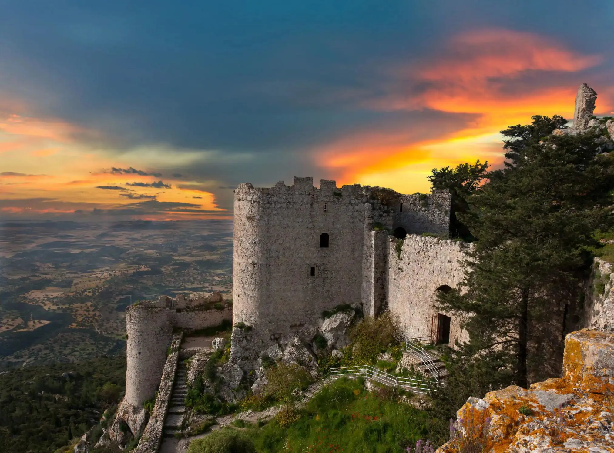 Ancient stone castle ruins on a hilltop overlooking the landscape of Northern Cyprus at sunset