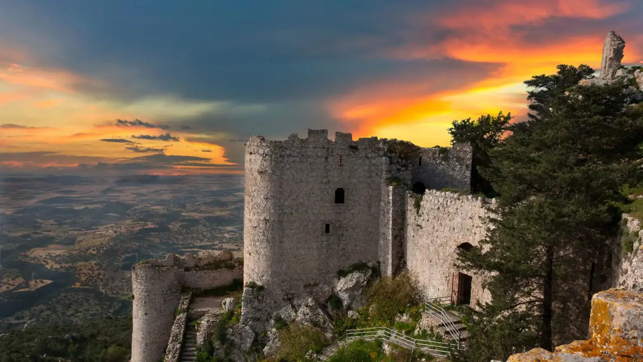 Ancient stone castle ruins on a hilltop overlooking the landscape of Northern Cyprus at sunset
