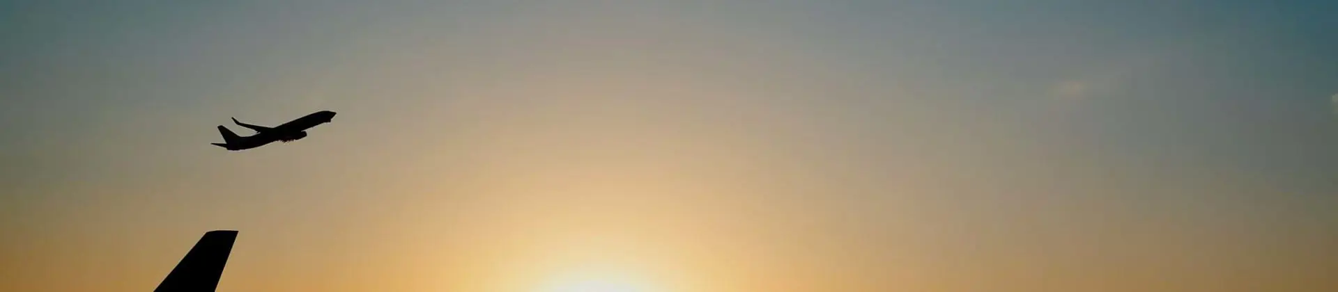 Airplane taking off at sunset over an airport 