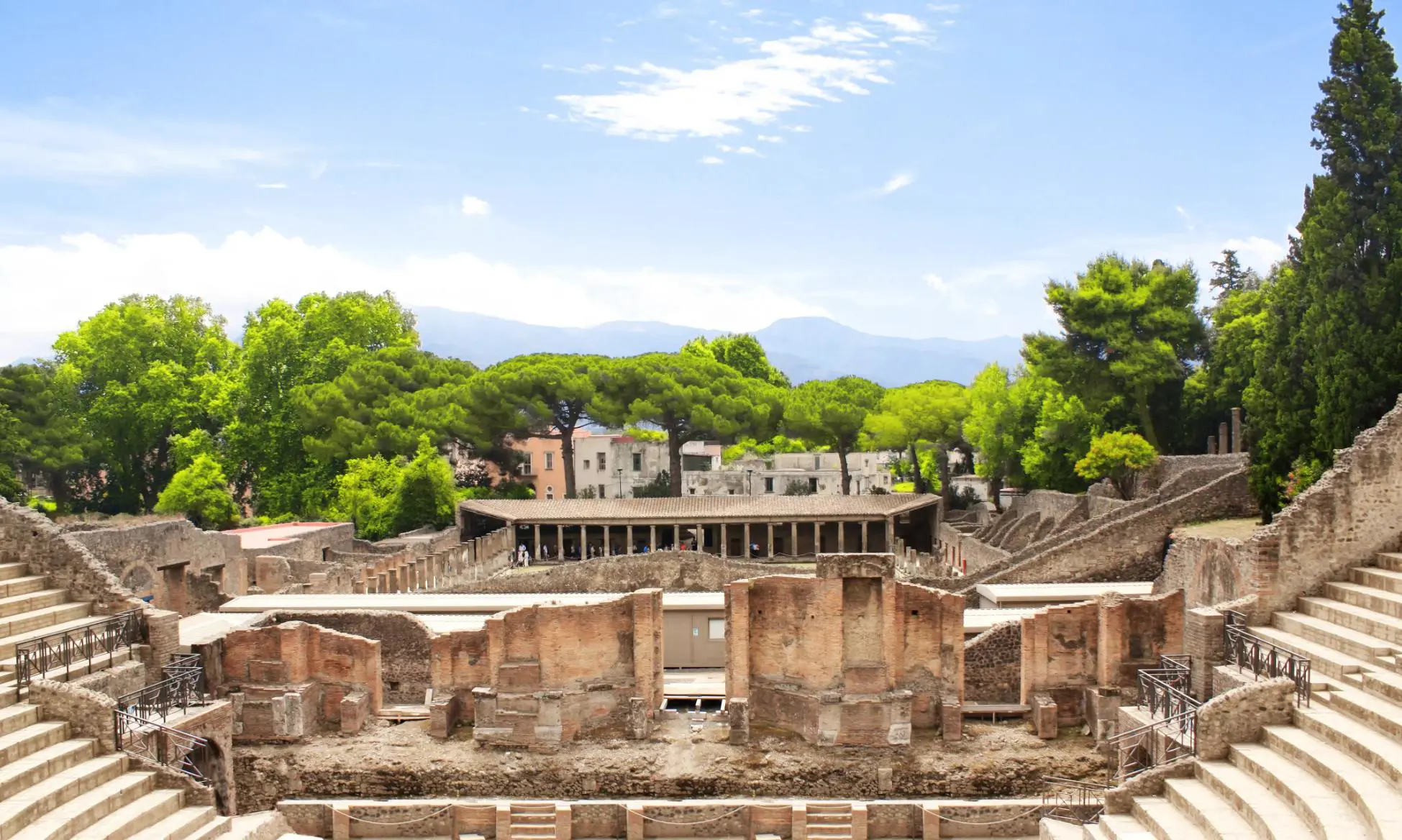The theatre district in Pompeii with the ancient theatre in the foreground and the Quadriporticus - a large rectangular courtyard surrounded by covered walkways visible behind it