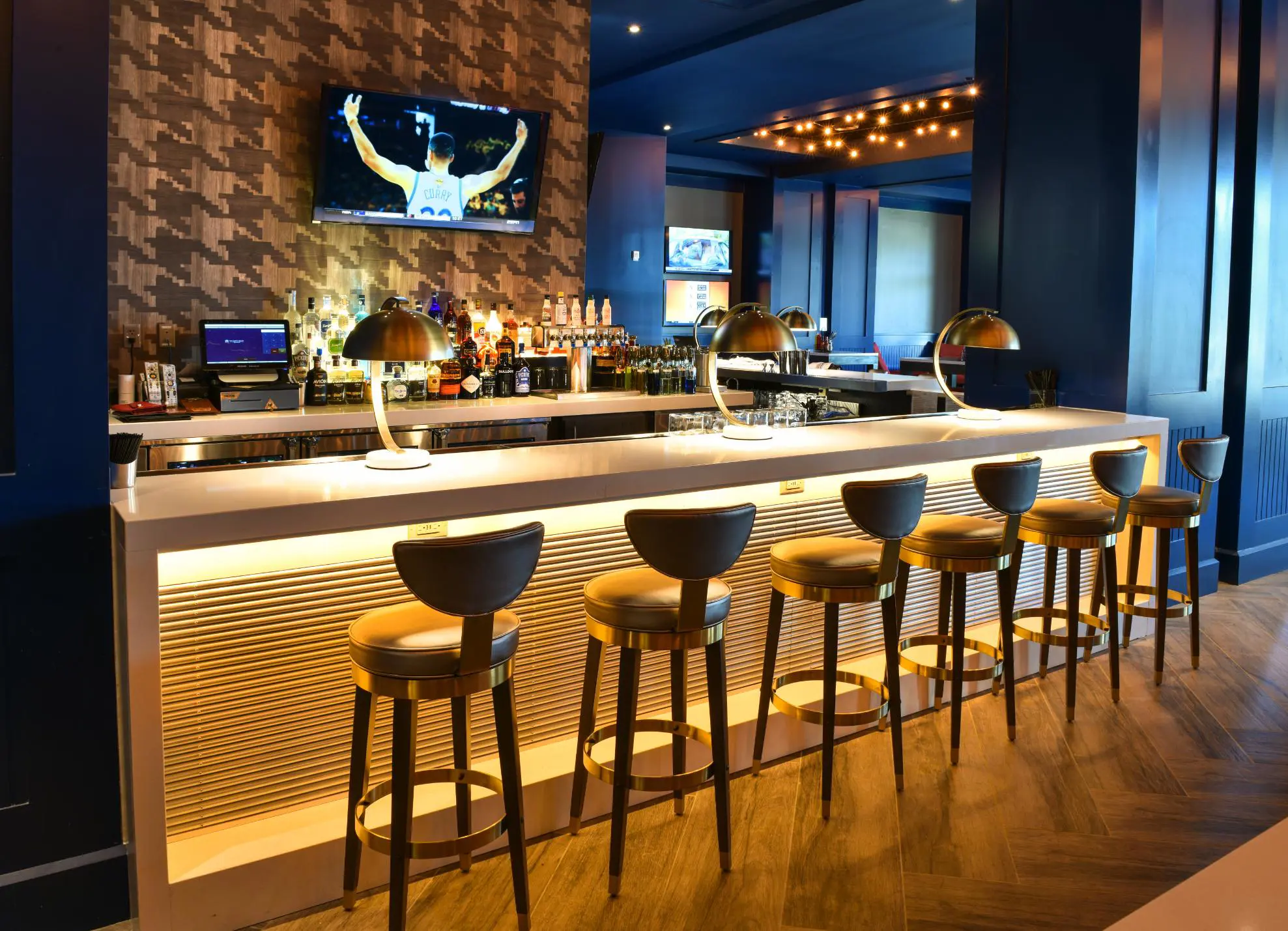 Stylish bar area at The Guest House at Graceland, featuring modern seating, golden lighting, and a sleek counter with drinks on display