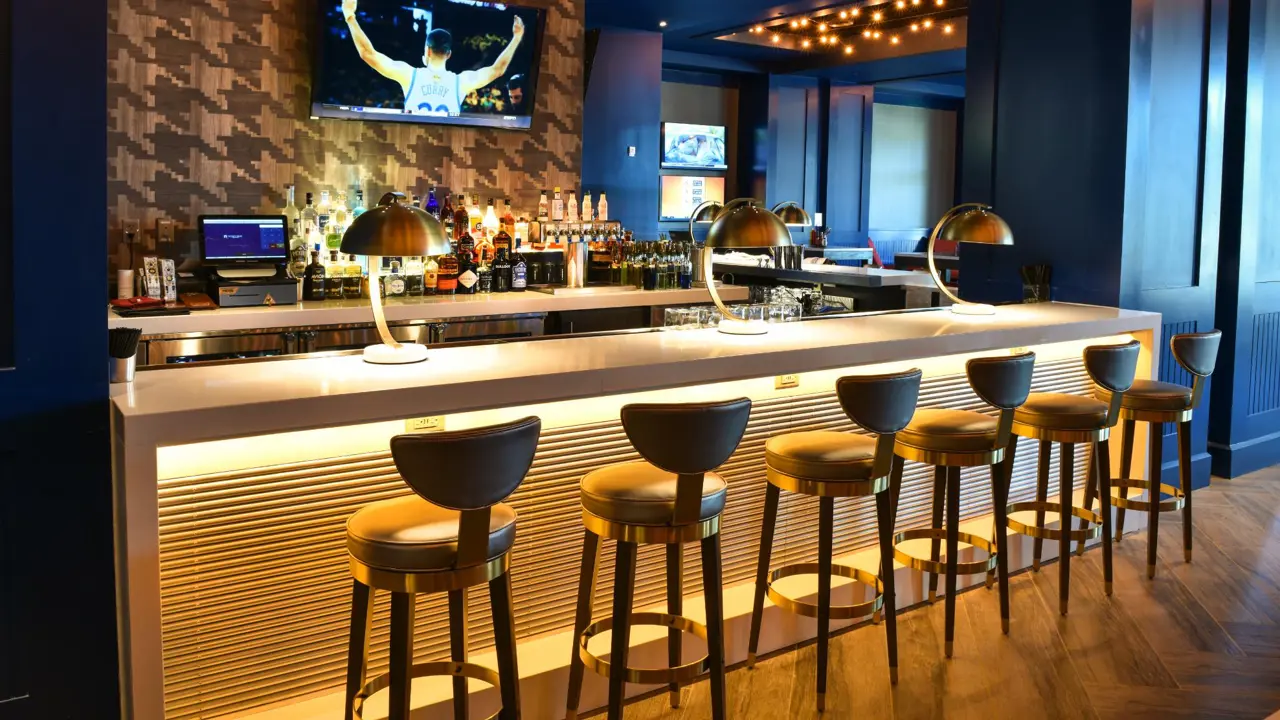 Stylish bar area at The Guest House at Graceland, featuring modern seating, golden lighting, and a sleek counter with drinks on display