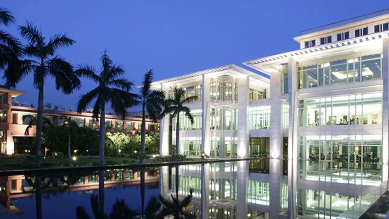 Jaypee Palace Agra’s illuminated pool area at dusk, reflecting the modern white architecture and palm trees